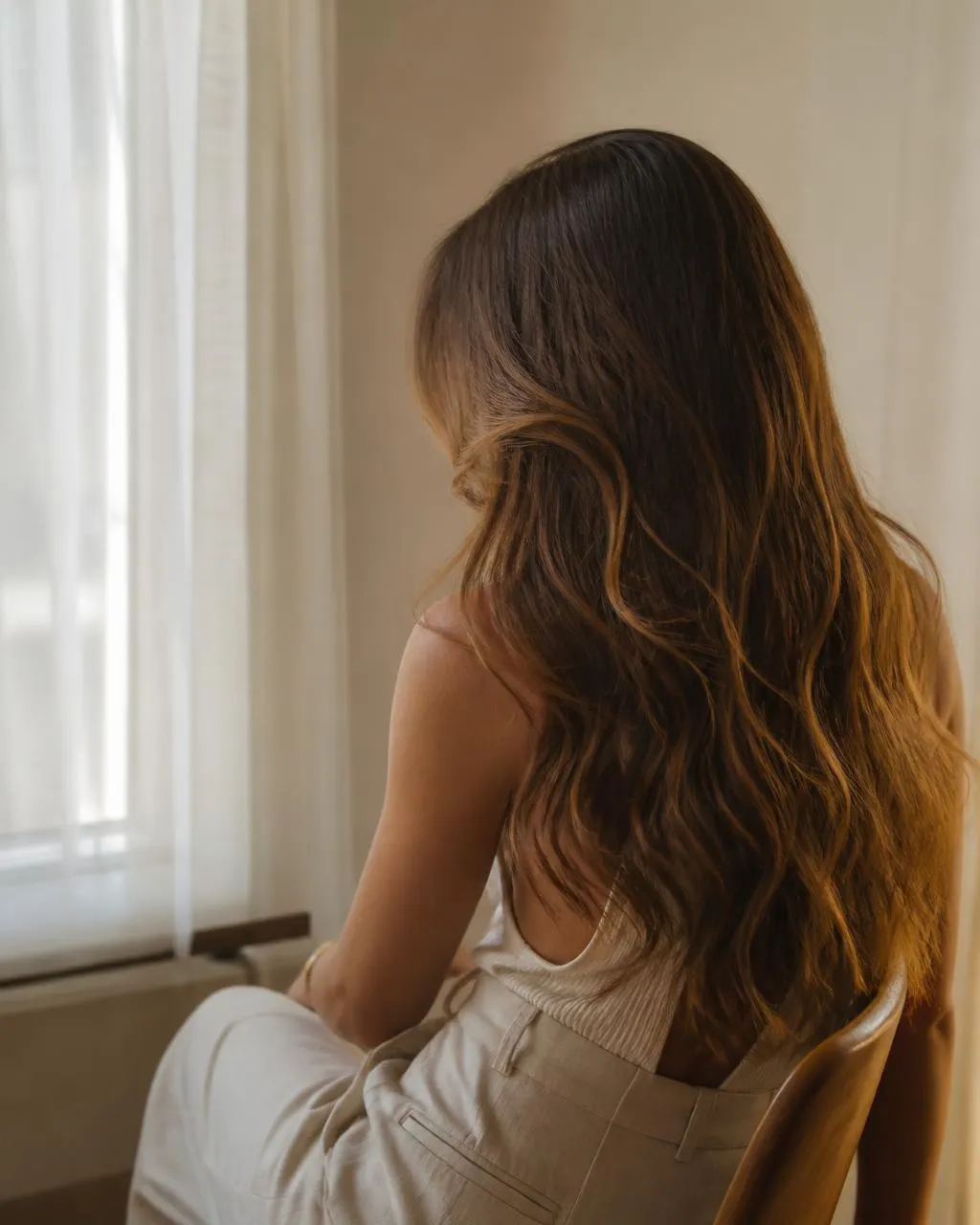 Woman with long wavy caramel-brown AVRÉE hair extensions in natural daylight